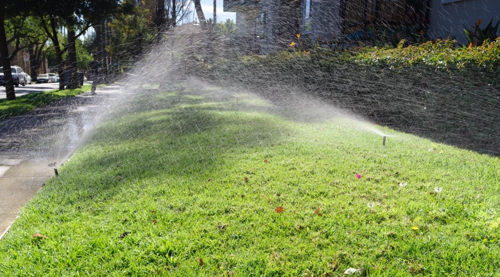 sprinklers watering the lawn outside an apartment complex